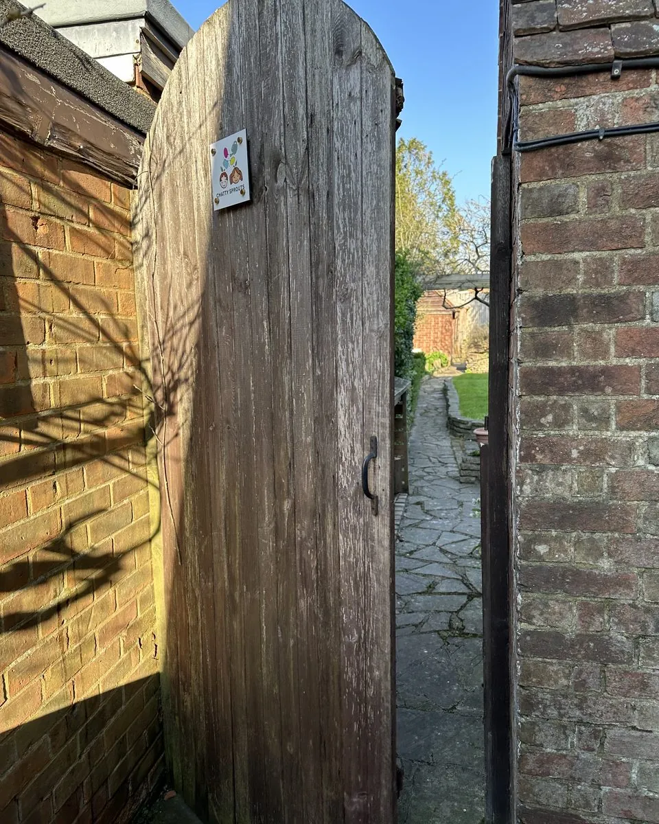 The side gate with the Chatty Sprouts sign, opening onto the garden path that leads to the studio.